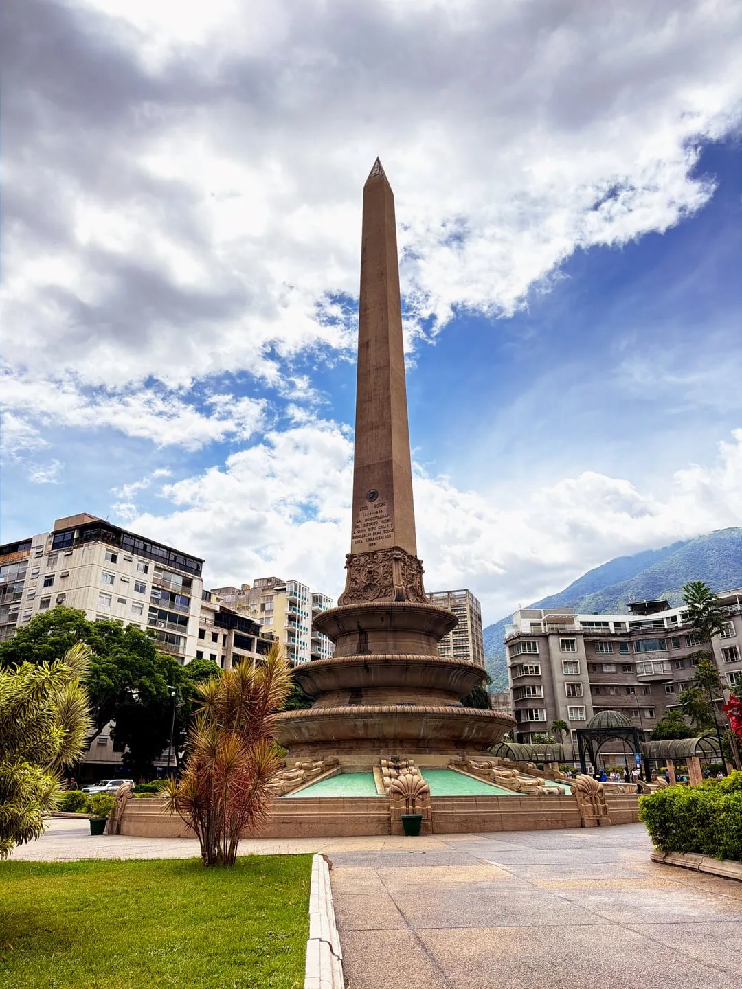 Plaza with an obelisk under a dramatic cloudy sky, shot with Nōma's Vivid recipe